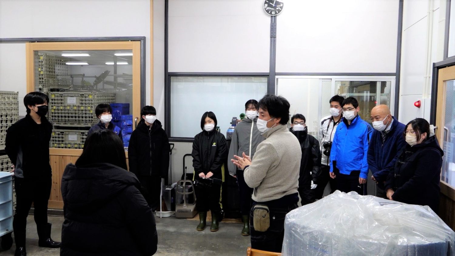 施設内で円になった高校生たちが、佐々木社長からワイン醸造に関わる説明を受けている様子の写真