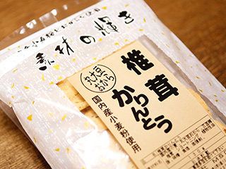 「椎茸かりんとう」と書かれたラベルのついたパッケージに入ったお菓子がテーブルの上に置かれている写真