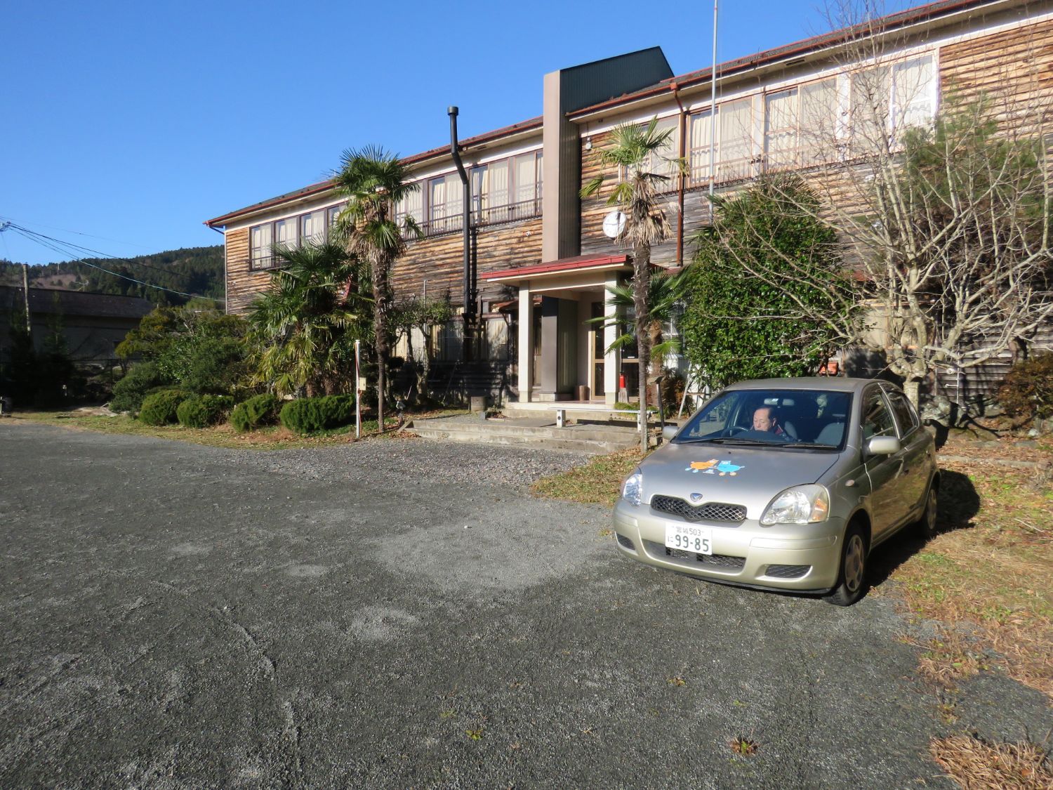 旧林際小学校の校舎の前にシルバーの5人乗りの乗用車1台が置かれた写真