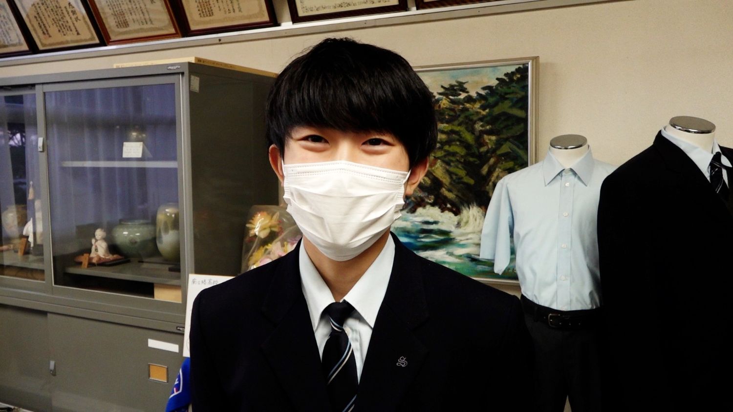 インタビューに答える、マスク越しにも明るい表情がうかがえる制服姿の男子高校生の写真