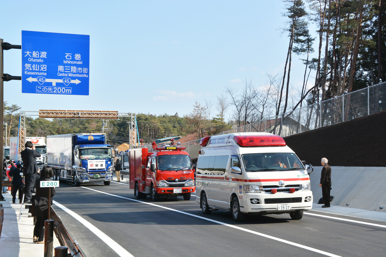 三陸沿岸道路の開通に合わせて救急車や消防車、大型トラックが新しい道路を次々に走り抜けている写真