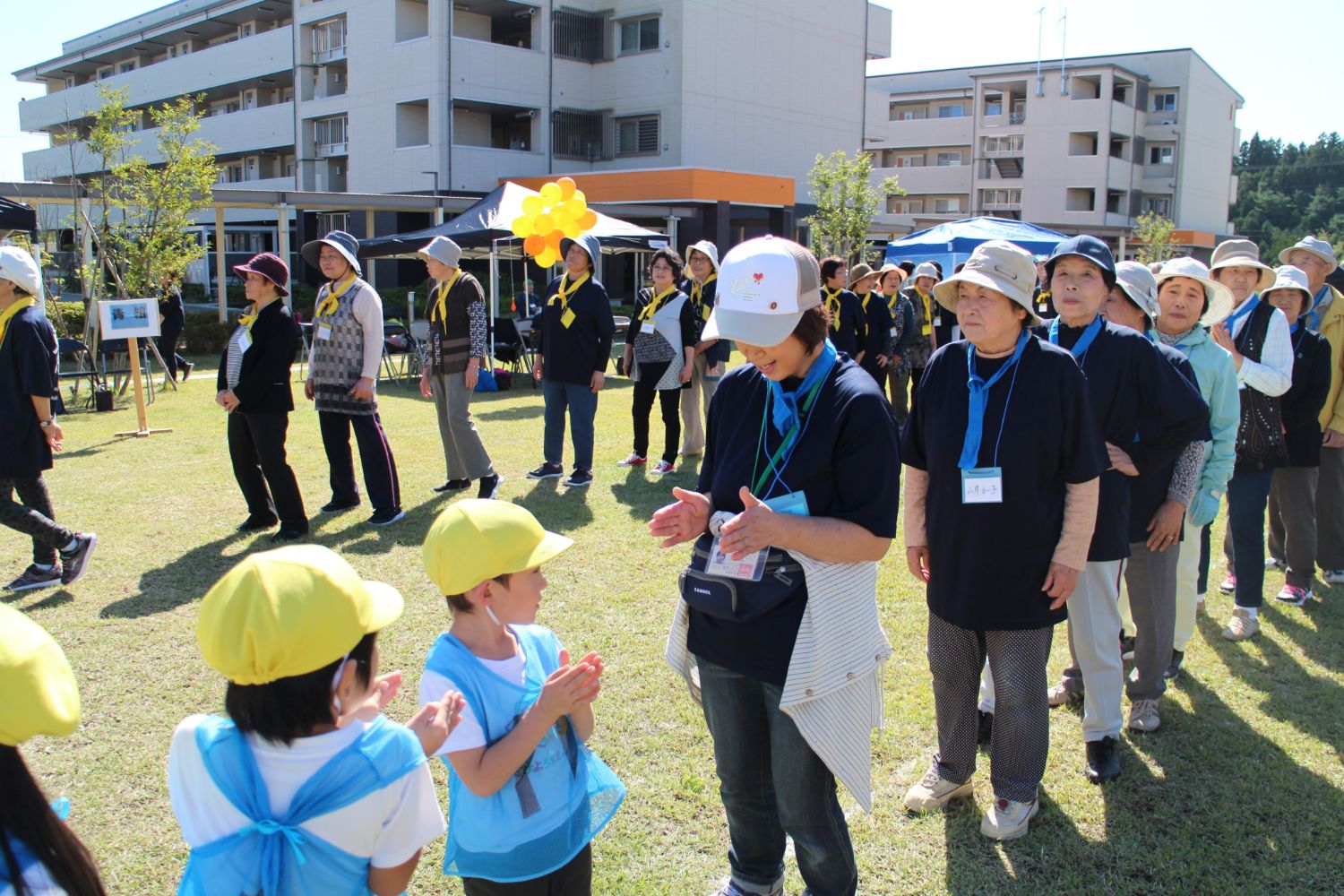 関係者の前ならえの真似をして同じポーズをする園児たちの写真