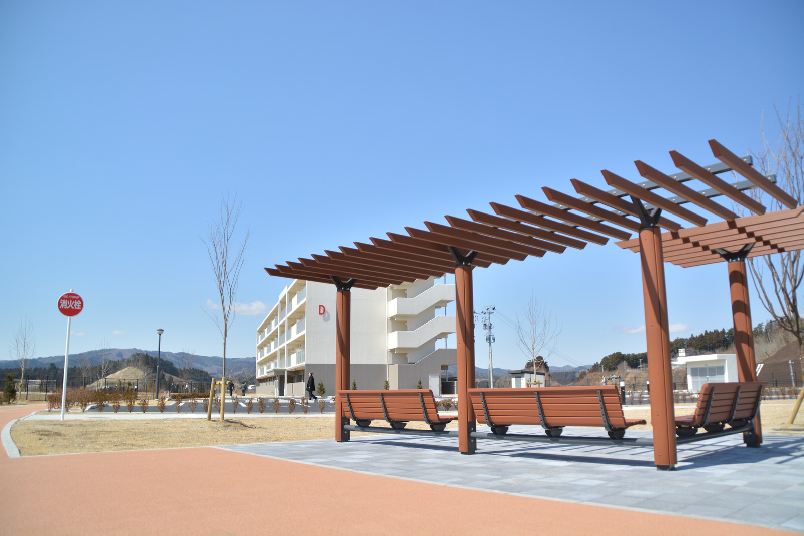 復興住宅の敷地内に日よけの屋根とベンチが置かれた憩いの場が設けられている写真