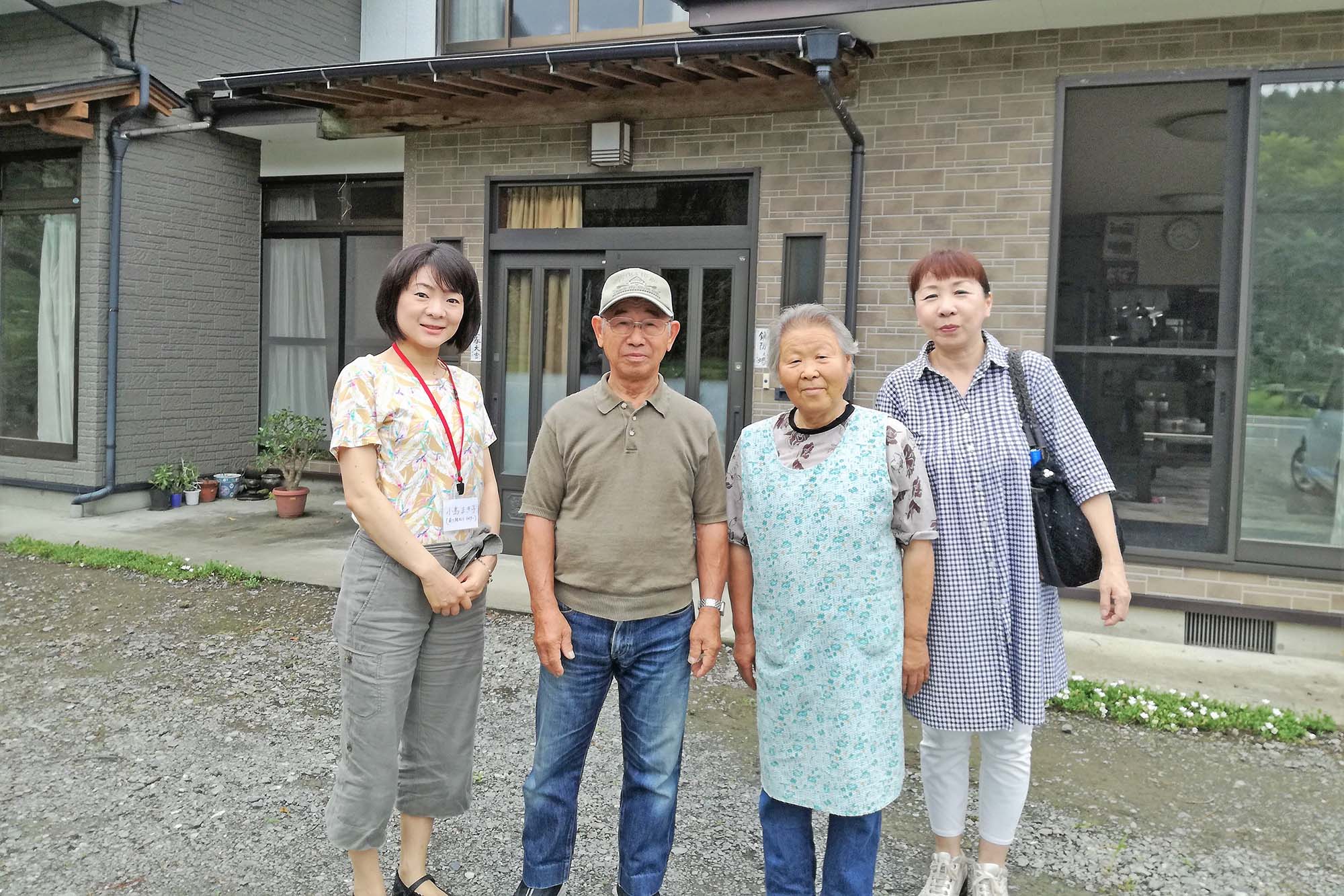 玄関の前で並んで立っている、首藤一雄さん・和子さんを中心に女性2人と写した記念撮影の写真