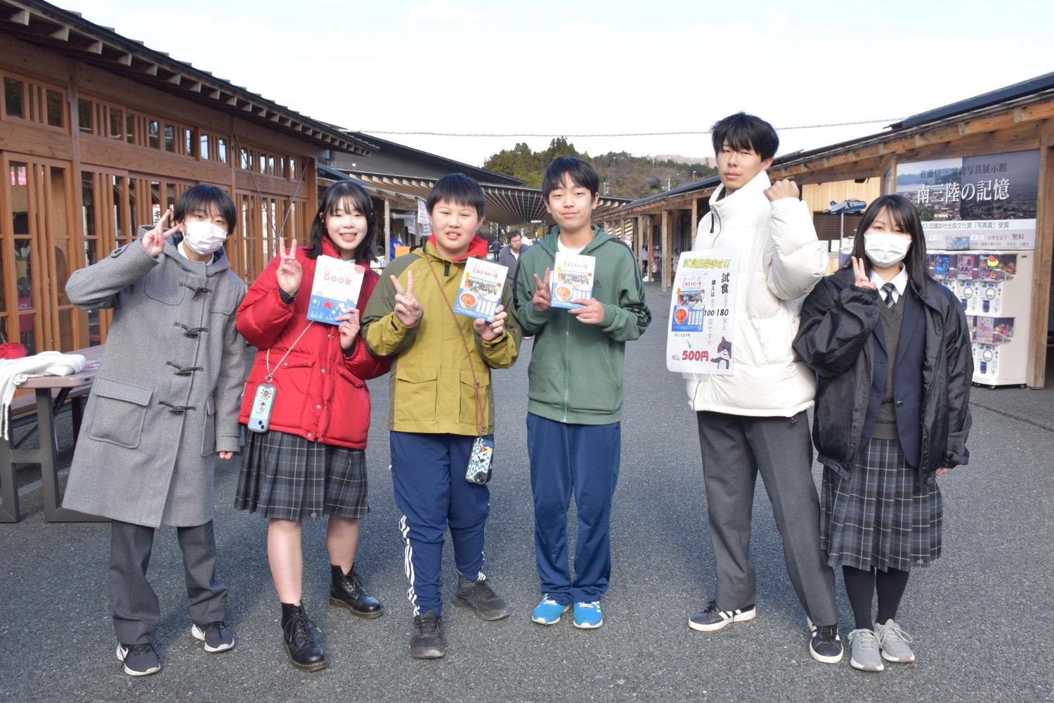 会場で、パンフレットなどを手に持った高校生たちが笑顔で並び、南三陸ミネストローネのPRをしている写真