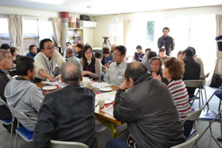 複数のテーブルが並べられ、グループに分かれて話し合いが行われ、地域住民やスタッフが和やかに意見交換している様子の写真