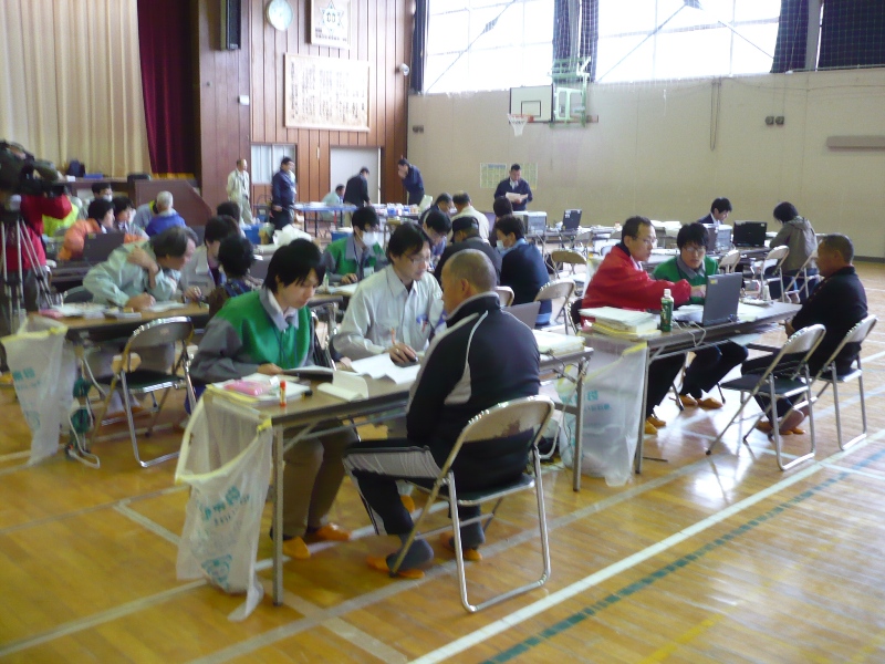 広々とした体育館の会場に複数の机と椅子が並べられ、職員の方々と訪れた町民の方が向かい合って座り、パソコンを使いながら税の申告をしている様子を写した写真