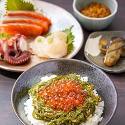 鮮やかなオレンジ色のいくらと深緑色のめかぶがお茶碗のご飯の上に盛り付けされている写真