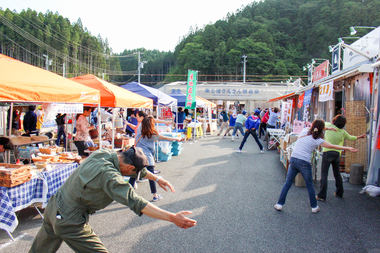 南三陸さんさん商店街の通りで人々が一緒に体操をしている写真