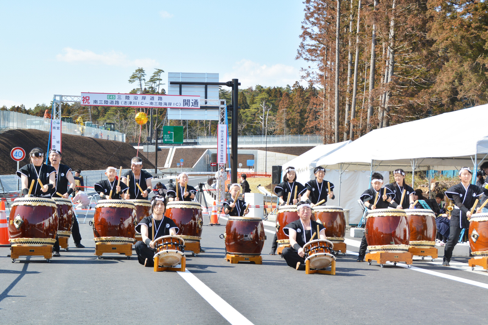 ゲートの前にたくさんの和太鼓が並び、黒い法被を着た大森創作太鼓のみなさんが力強く演奏をしている写真