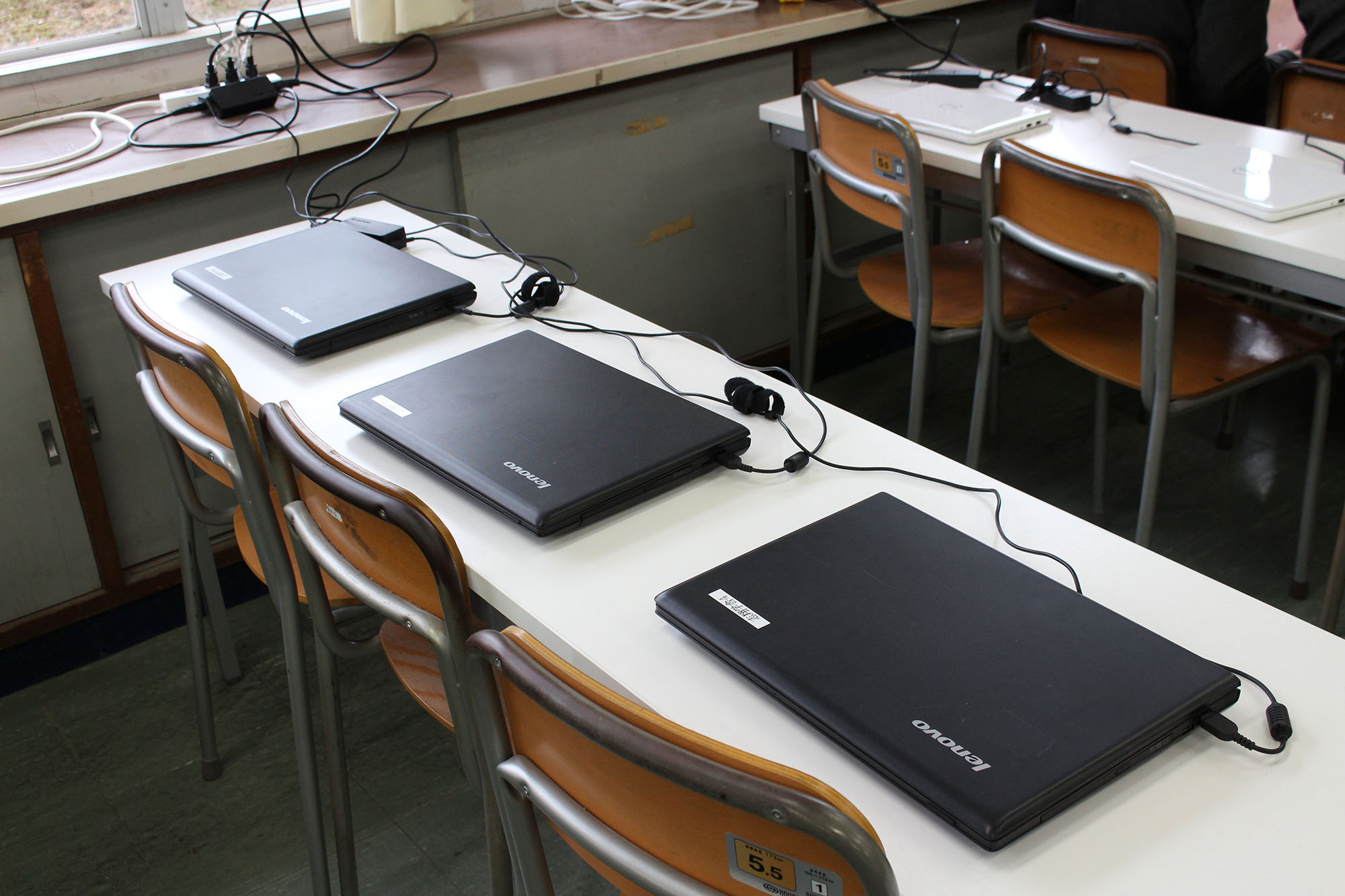 3人が座って利用できる長机に、3台のパソコンが並べて置かれている写真