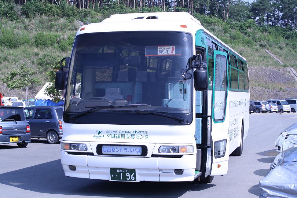 白い車体で、前方のフロントガラスに「がんばろう東北」と掲示された大型の仙台セントラルバスが駐車場に停車している写真