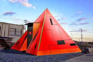 赤いピラミッド形の近未来的なCGデザインで、表面に黒い幾何学模様が描かれているピラミッドの写真