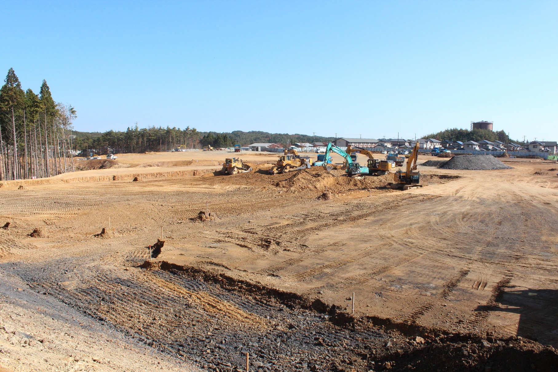 開発中の広大な土地で、複数の重機が土を掘り起こしている様子が写っている写真