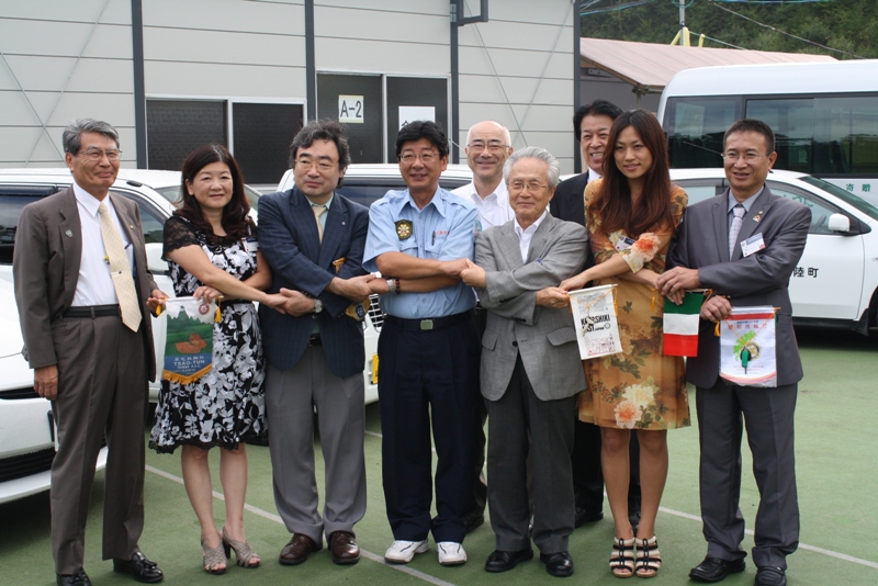 町長と関係者の方々が互いに手を取り合い、笑顔で記念撮影している様子の写真