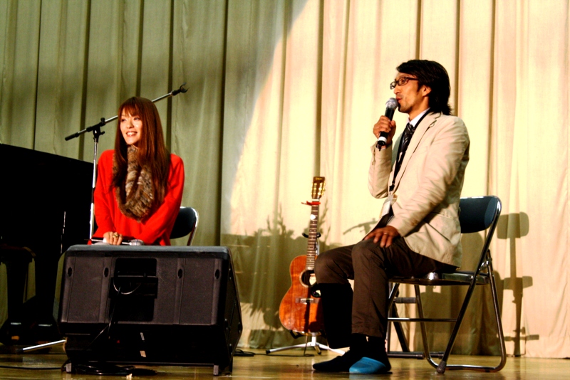 ステージ上で今井絵理子さんと関係者の男性が椅子に座り、マイクを手にトークをしている様子の写真