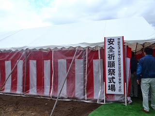 「安全祈願祭式場」と書かれた看板が立つ紅白幕が張られたテントに人々が入っていく様子の写真
