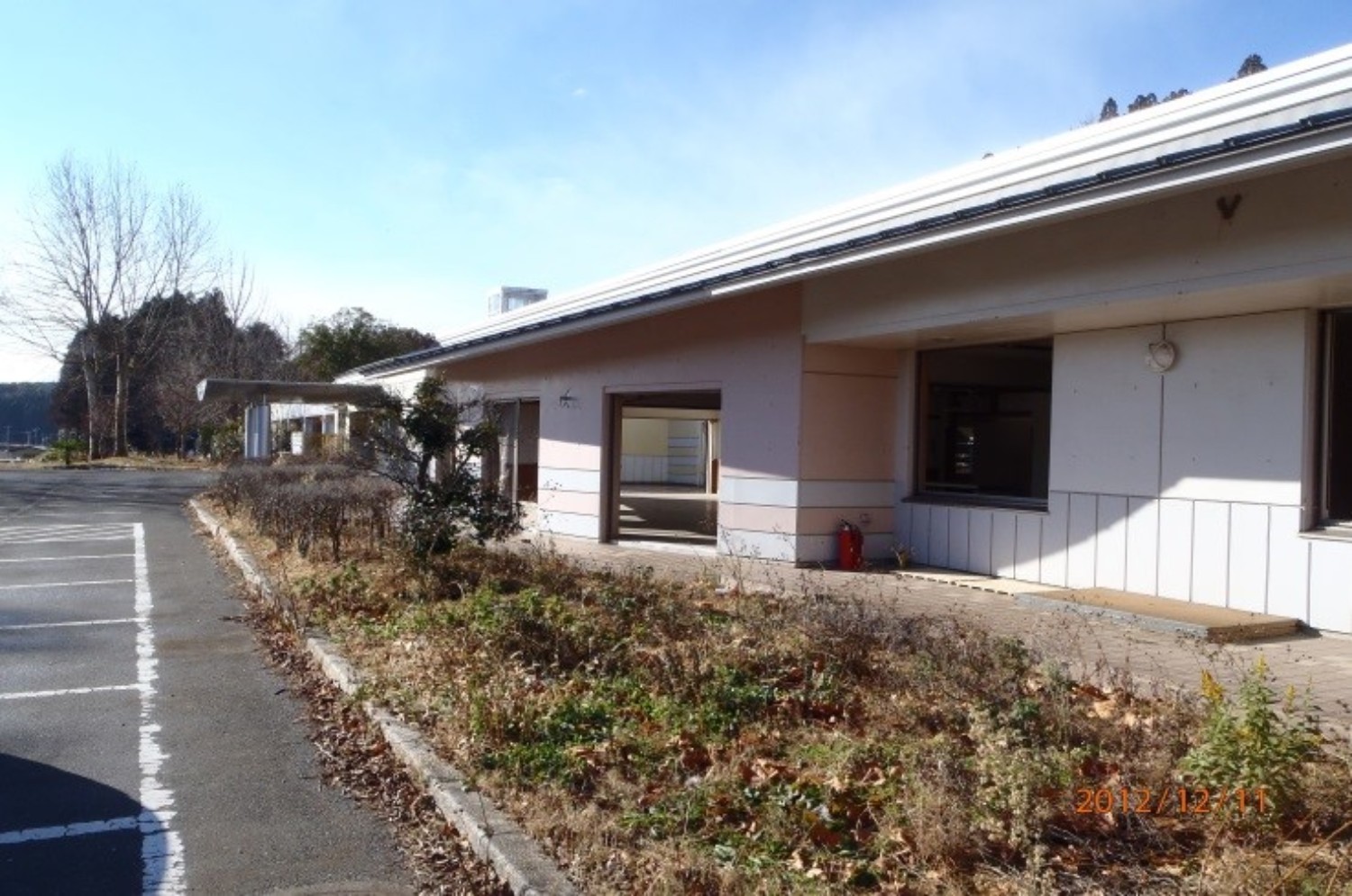 草が生い茂った敷地に面して建つ、震災前ののぞみ福祉作業所の建物の外観を写した写真