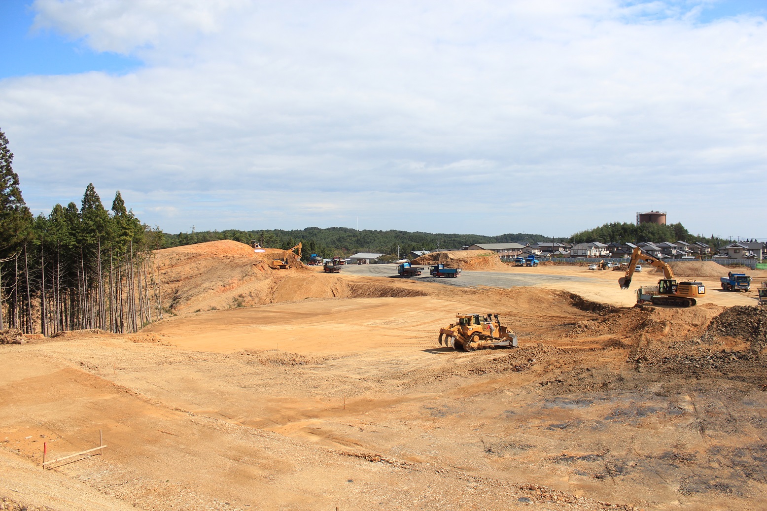 広大な建設現場で複数の重機が稼働している様子を示している写真