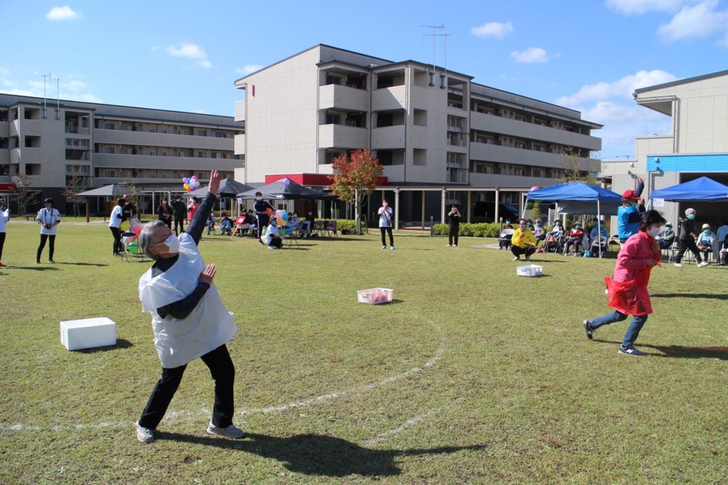 芝生の広場で白色、赤色、水色の衣装を着け踊っている様子の写真