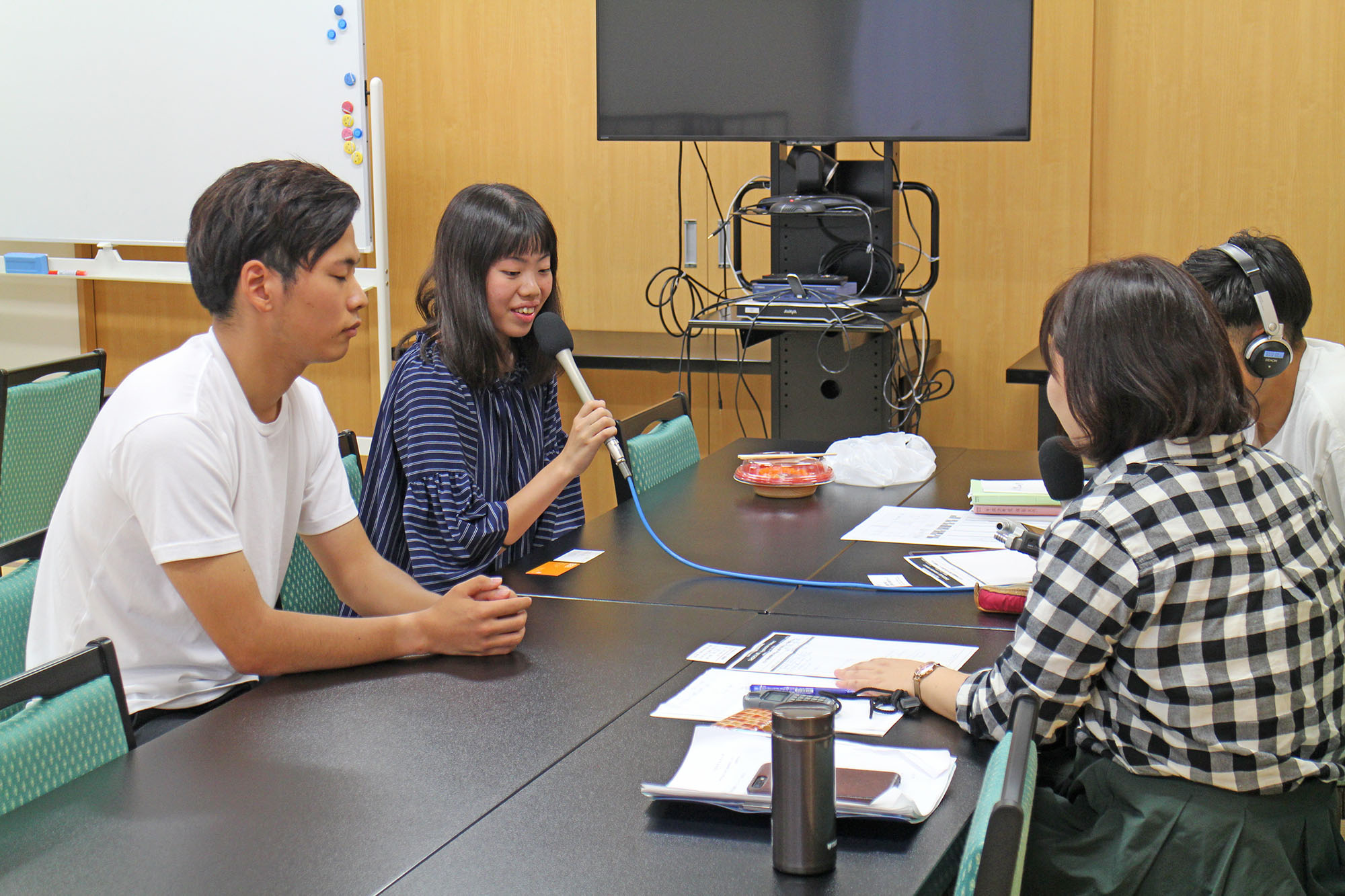 鈴木さん、小坂さんと、女性リポーター、男性スタッフがテーブルを囲んで向かい合い、インタビューをしている写真