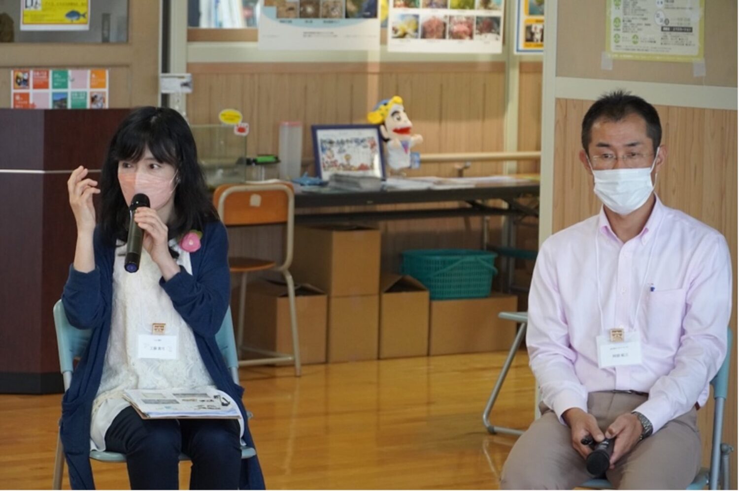 会場内の教室で工藤真弓さんがマイクを持って発言し、隣で阿部拓三さんが座って聞いている様子の写真
