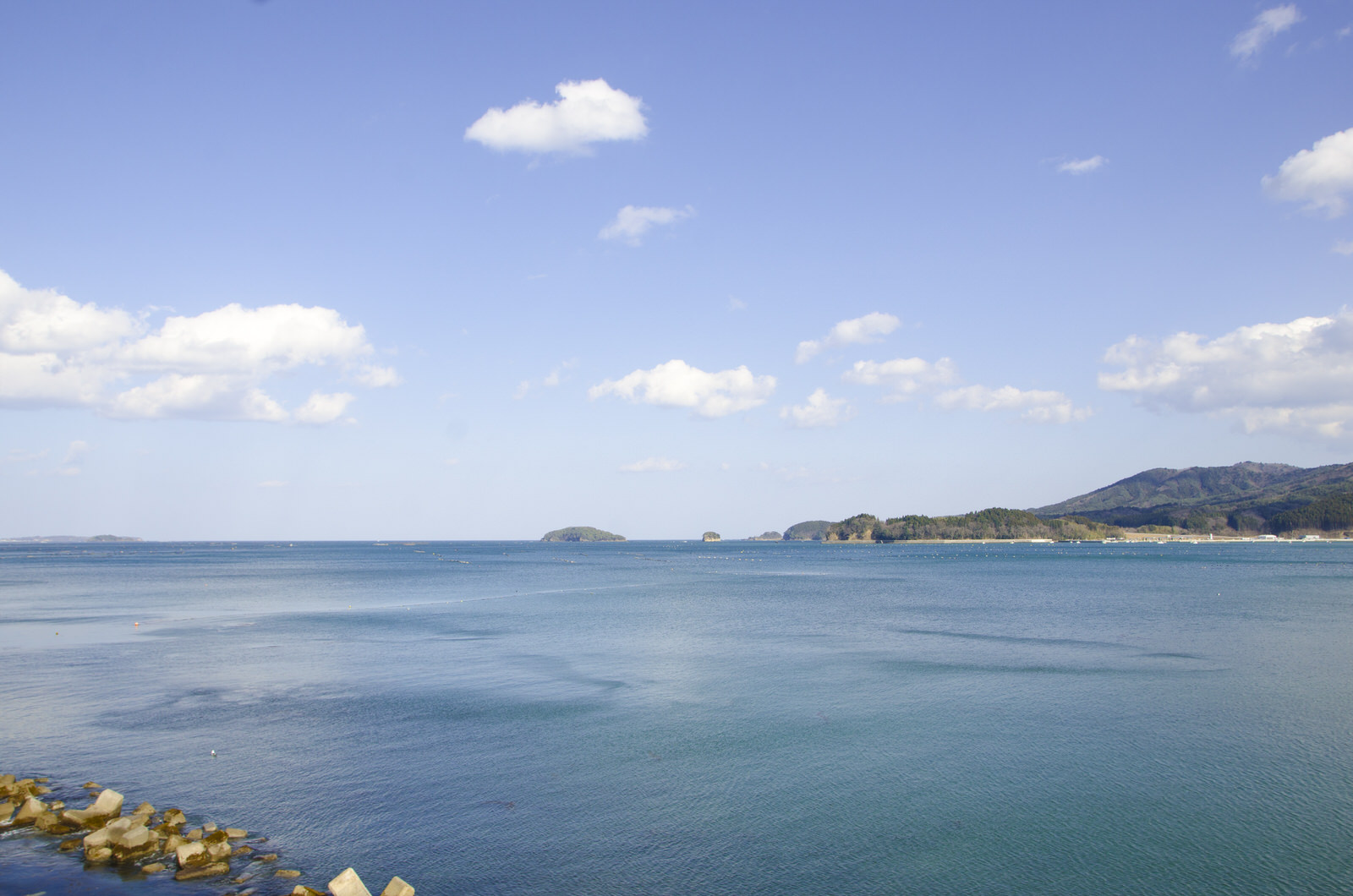 青空の下、穏やかな海が広がり遠くの島や陸が見える写真