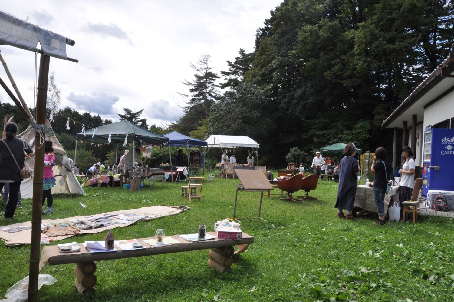 複数のテントが並んだ広場に多くの人が集まり、クラフトや食べ物などを楽しんでいる様子が見えるマルシェ会場全体の写真