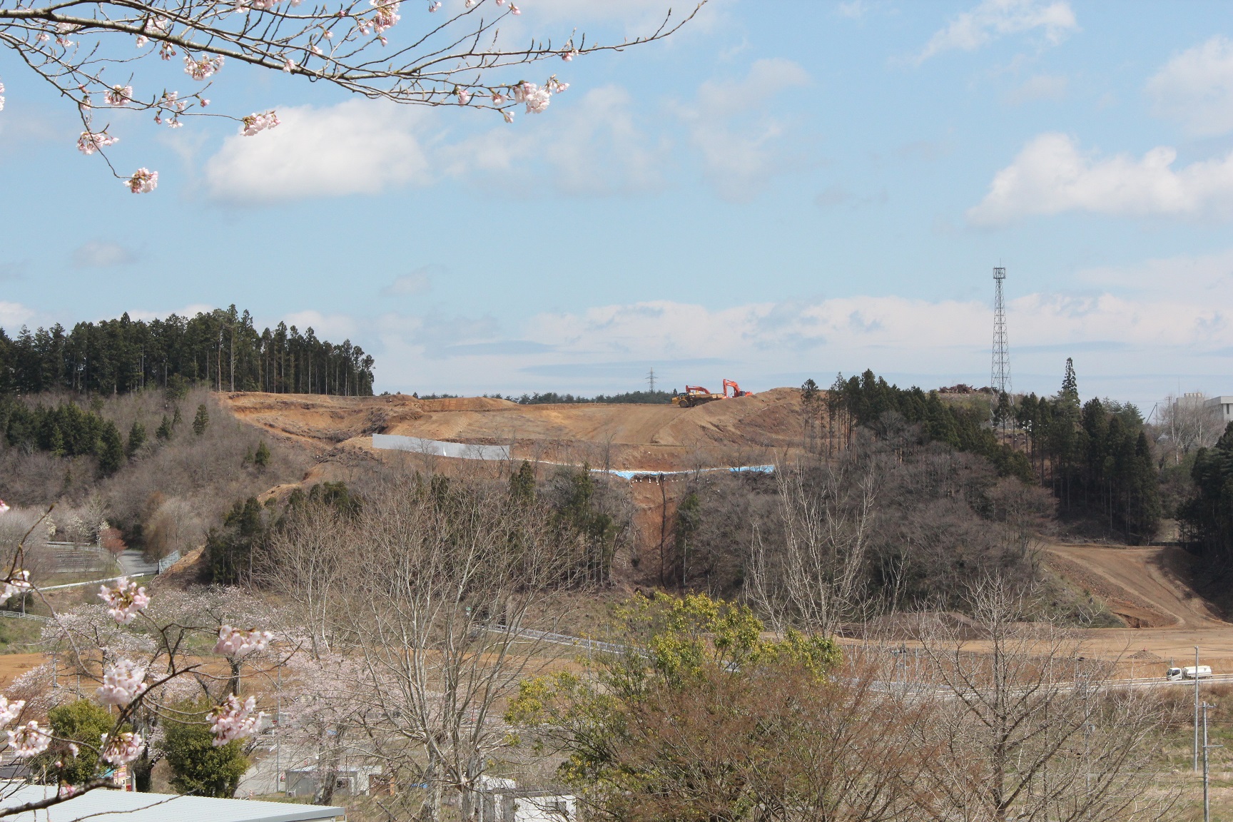 造成工事が進められた遠くの造成地に複数の重機が見られる写真