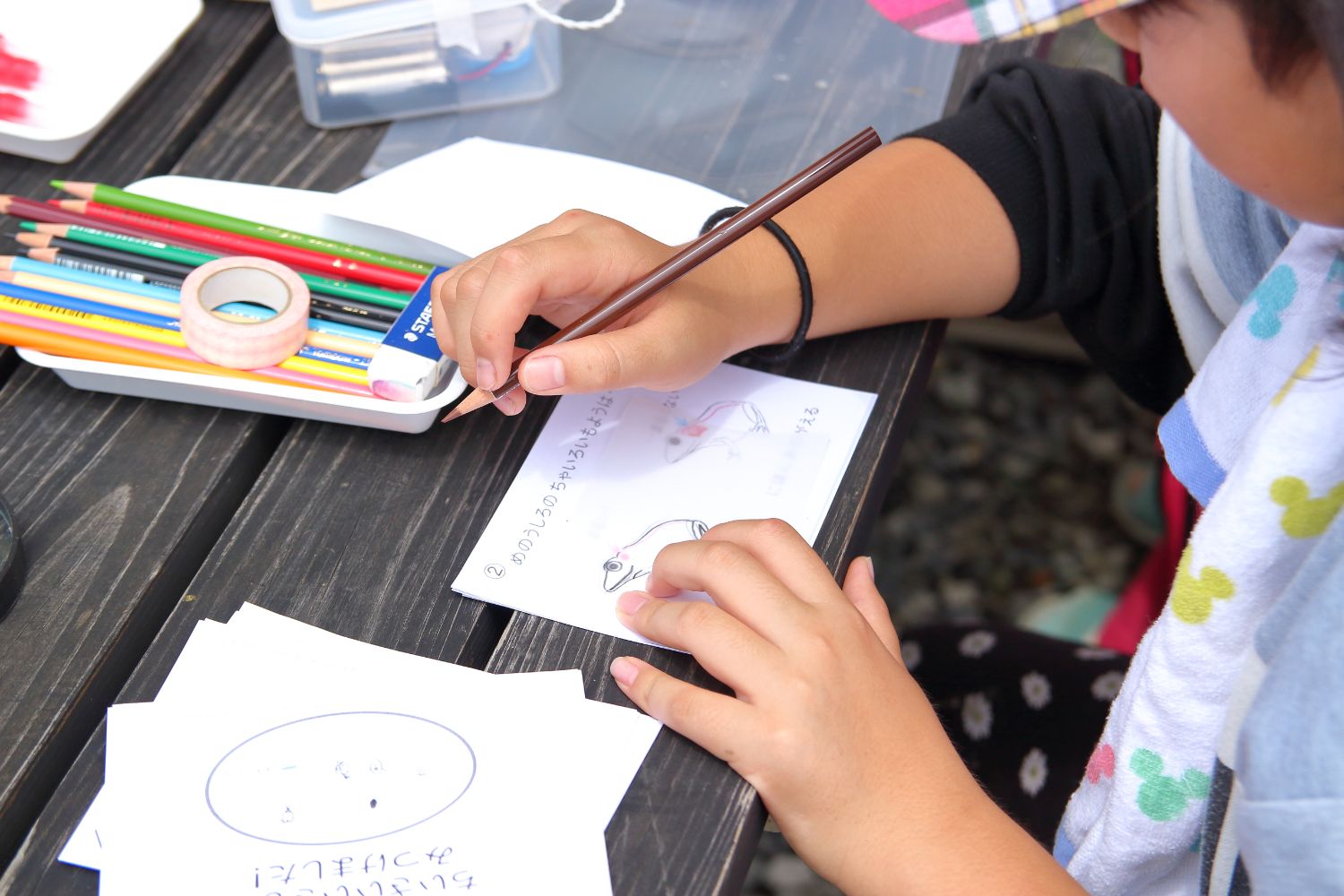 子どもが捕まえた生きものの絵を観察カードに色鉛筆で描いて記録している様子の写真