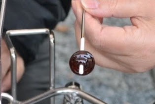 金属棒の先にある、形を整え茶色に変化した小さなガラス玉がついている手元をアップで撮影した写真