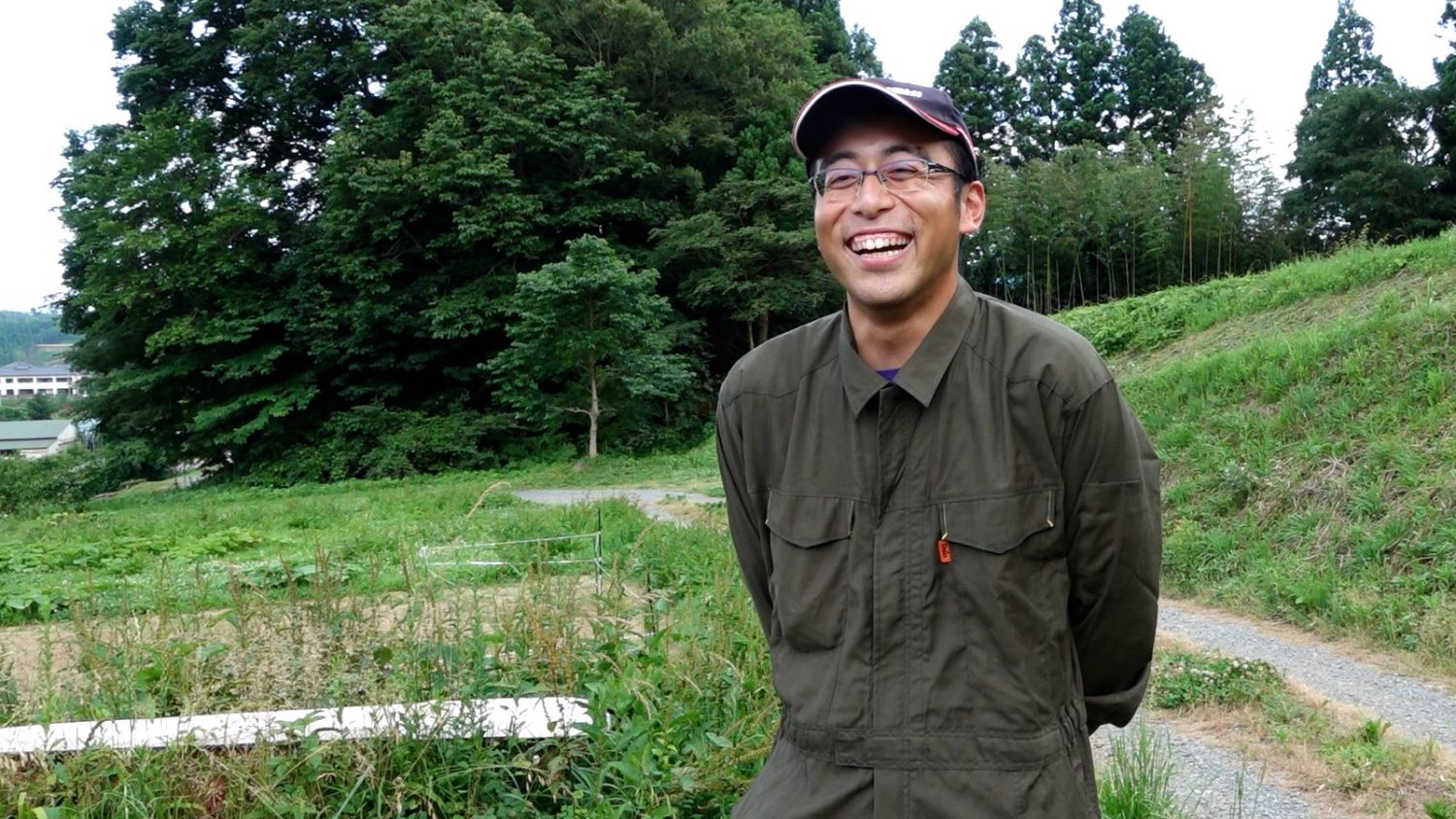 緑の斜面の前で太田一さんが笑顔で立っている写真
