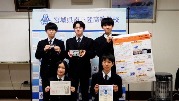 南三陸町の高校生たち5名が特産や名所を盛り込んだオリジナルナンバープレートの完成品やデザイン案を手に持ち、プレゼン用のポスターとともに記念撮影をしている写真