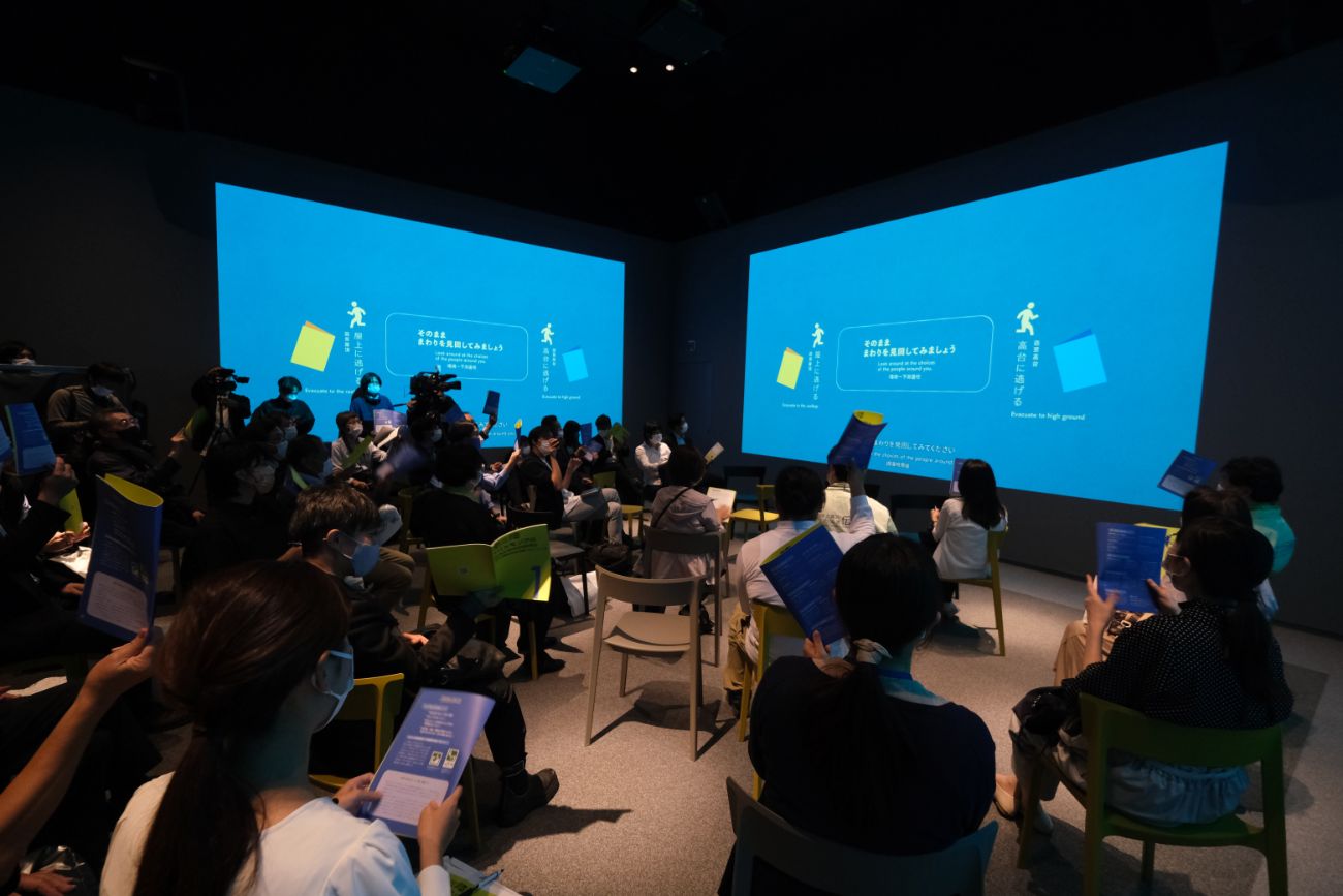 来館者がスクリーンに映し出された震災当時の映像を真剣に見ている様子の写真