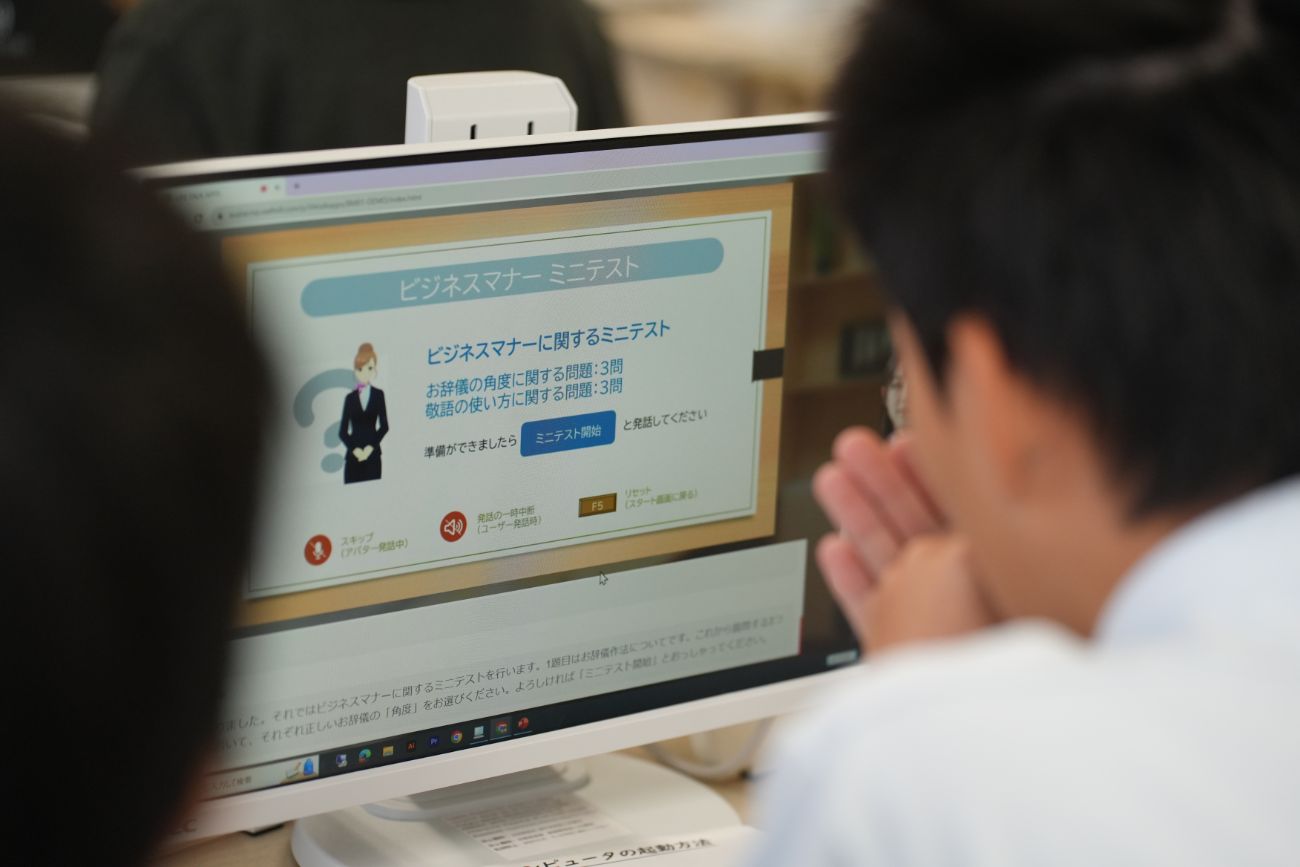 パソコンの画面にビジネスマナーに関するミニテストの画面が映っていて、2人の受講者が問題を確認しながらテストを受けている様子の写真