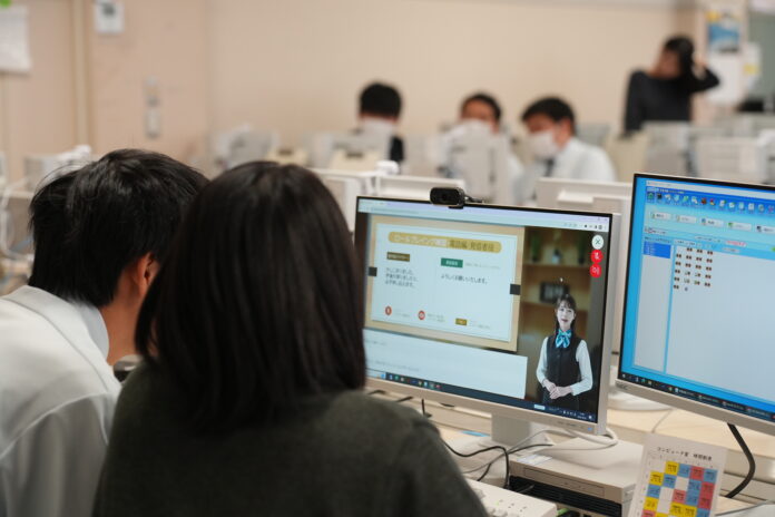 二人の学生がパソコン画面のビジネスマナーのAIアバター講義を一緒に視聴している様子の写真