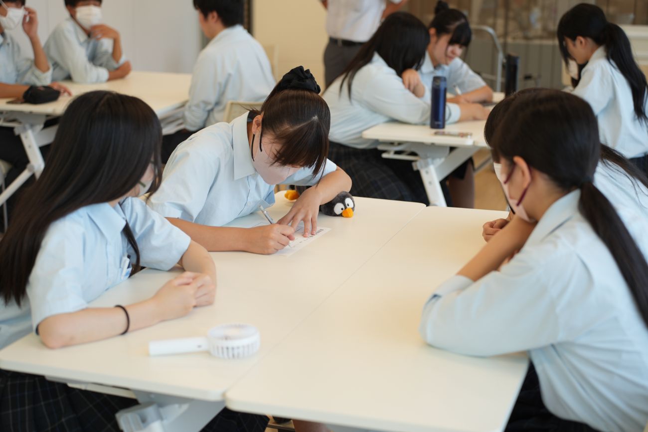 学生たちがグループに分かれて机を囲み、話し合いや作業をしている様子の写真