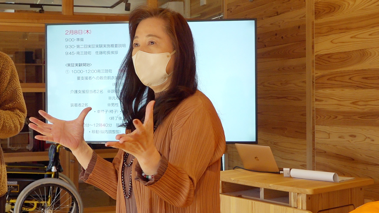 スクリーンの前で馬朱美社長が手を広げて話している様子の写真