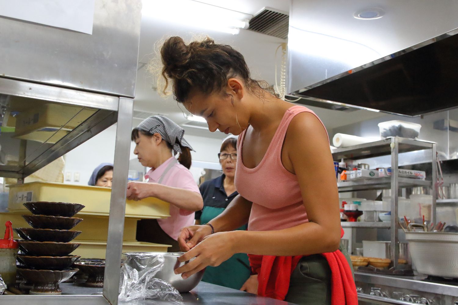 ピンク色のタンクトップを着たタティアナ・タギルさんがボウルを覗き込み料理を作っている様子の写真