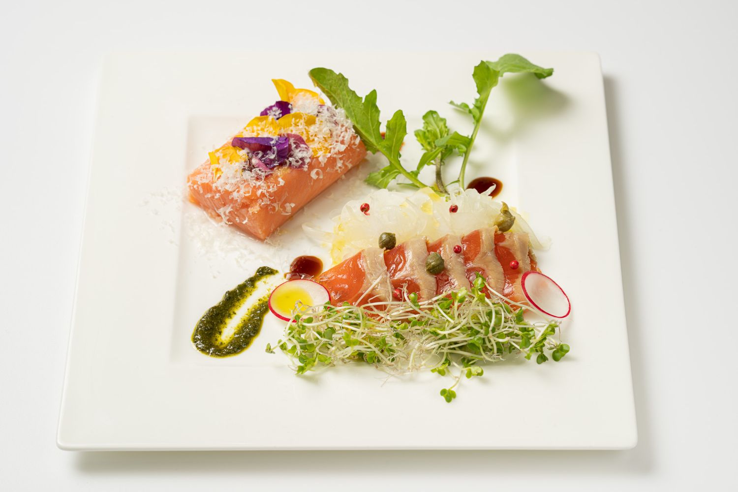 おしゃれに盛り付けられたサーモンの前菜が白い皿にのっている写真