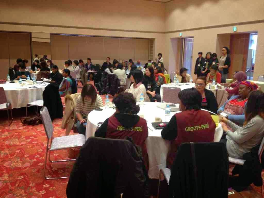 広い部屋の中に複数の円卓が配置され、それぞれのテーブルには数人が座って読書や筆記、会話などに取り組んでおり、壁際や出入口付近には立っている人も見られる勉強会での写真