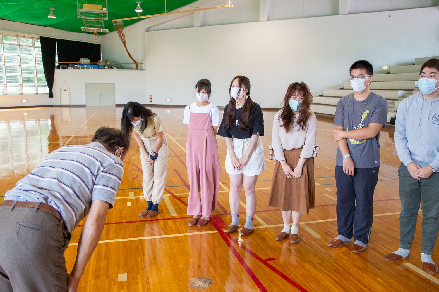 体育館の中で若者たちが横一列に並び、村岡会長に対して丁寧にお辞儀をして感謝の気持ちを表している様子の写真