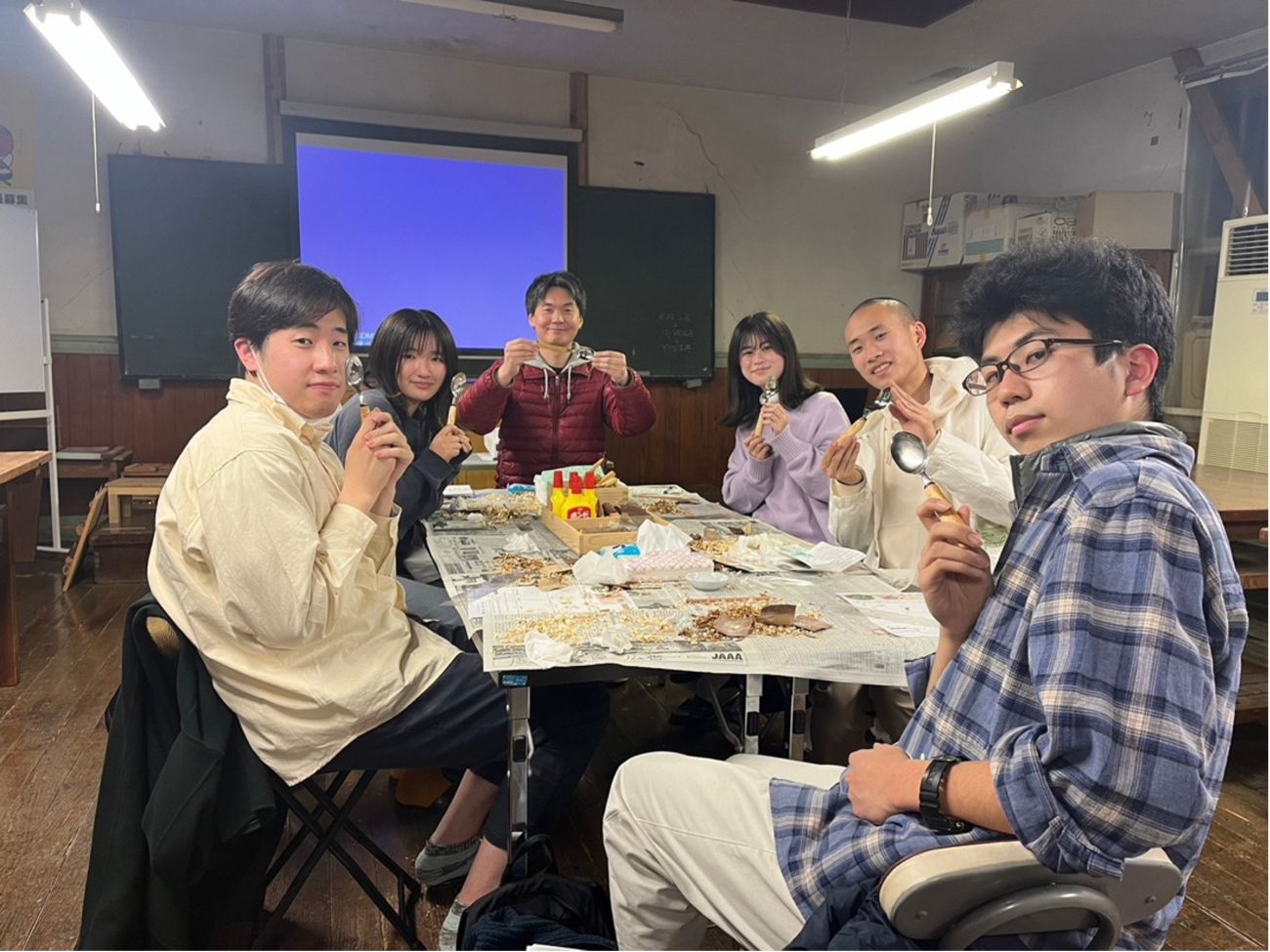 みんなスプーンを手に持ち、テーブルを囲んで6人の若者が座っている写真