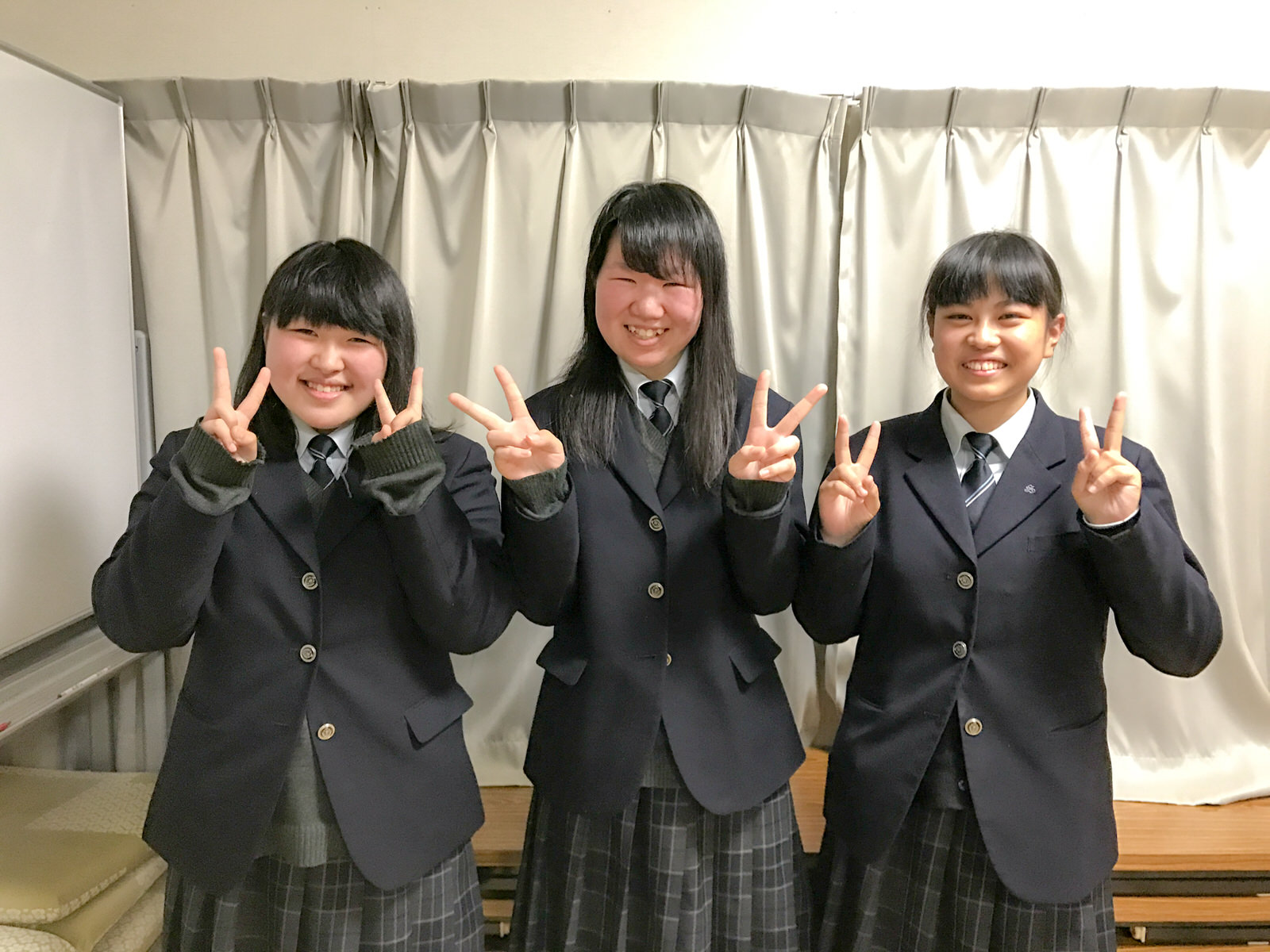 三人並んで両手でピースサインをしている制服姿の女子高校生の写真