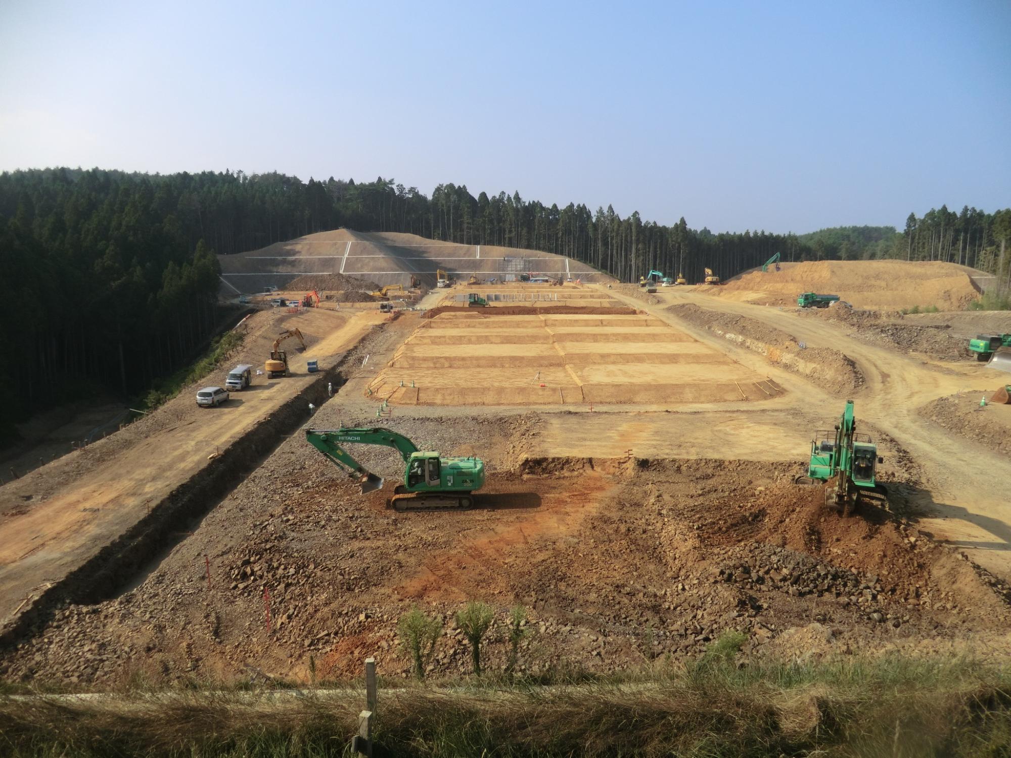 広い造成地で重機が掘削作業を行っている、造成工事中の高台整備の写真