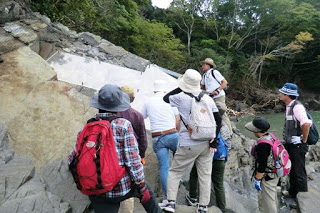 大きな岩の一部がガラスで保護ざれており、その周りに参加者たちが集まって中を観察している写真