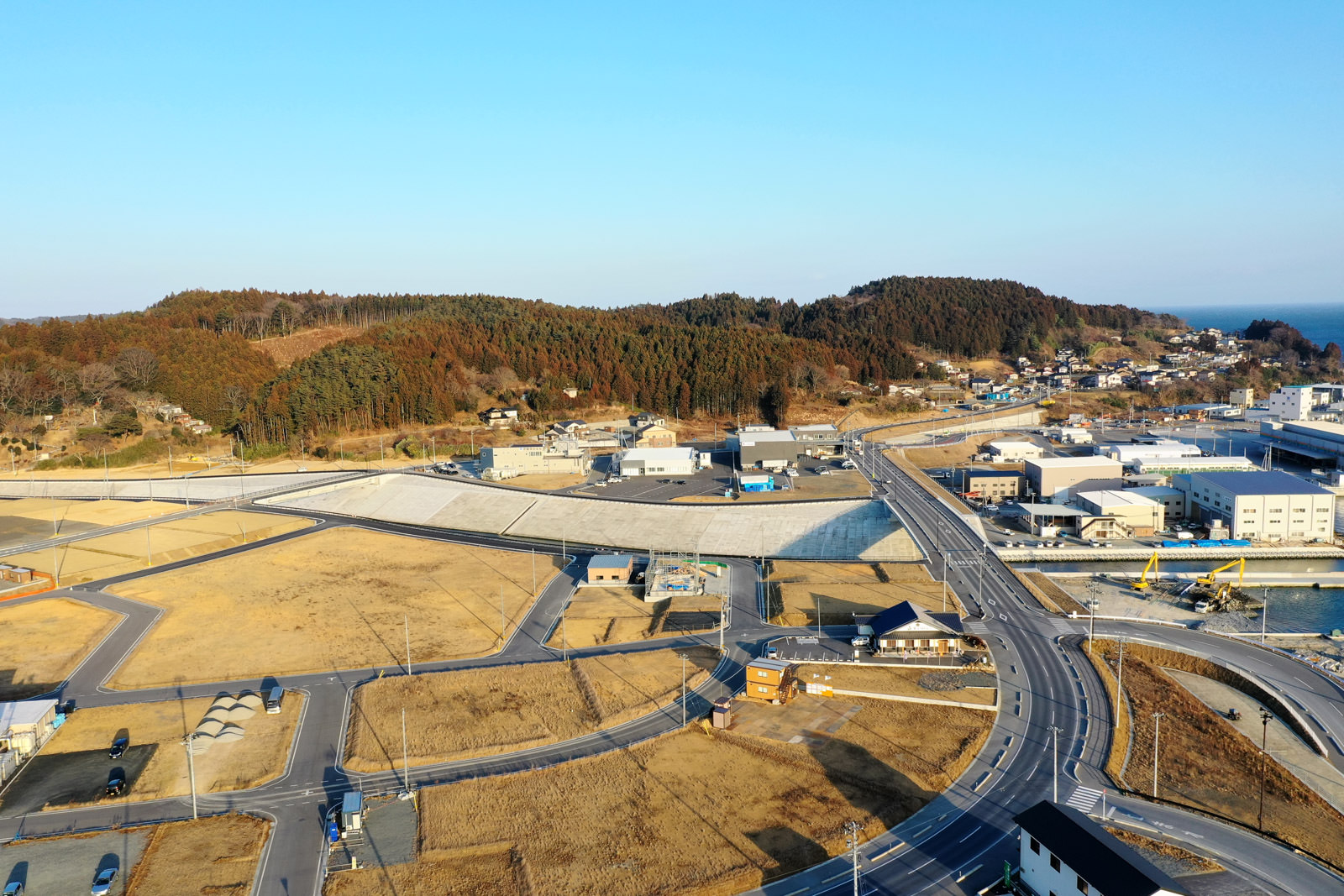 山々に囲まれた田舎の町の風景で、谷間に沿って道路が通り、いくつかの建物が点在している様子が確認できる静かな地域の写真