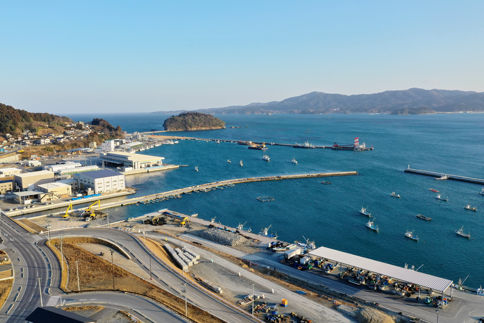海に面した港町の風景で、岸沿いに複数の建物や道路が整備され、船が停泊している様子が見える静かな海辺の町の写真