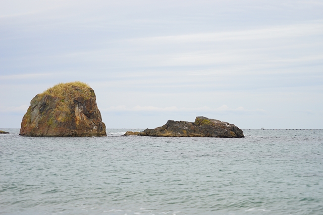 横たわったモアイのように見える岩山が海の中に見えている写真
