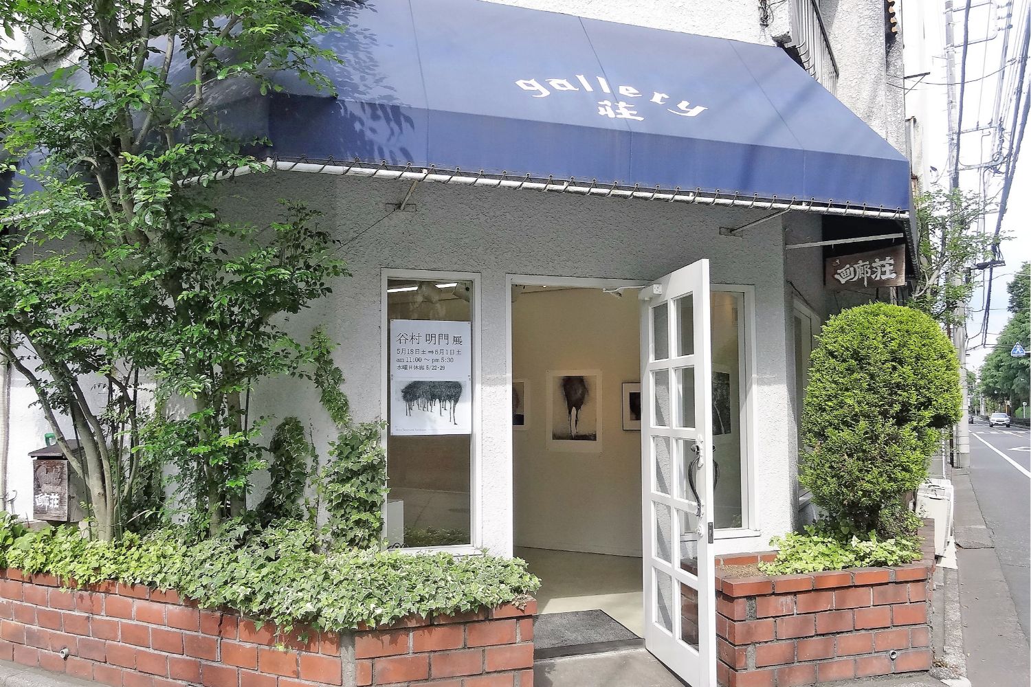 木々とレンガに囲まれた『gallery荘』と書かれた画廊の入口があり、扉が開いて中に作品が展示されている写真
